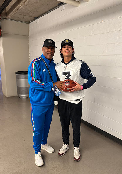 Alé holding an NFL football with a coach