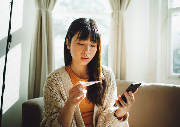 Getting the most out of virtual care. Woman looking at a thermometer while talking to On Demand Care clinician. 