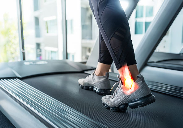 a female running on the treadmill with ankle pain. 